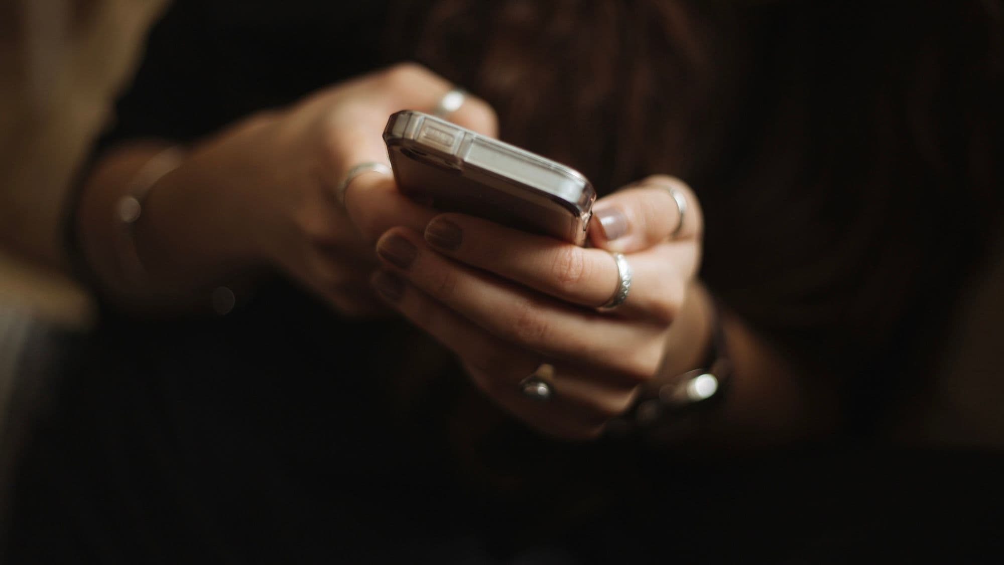 Close-up photo of a person holding a smartphone in both hands and apparently looking at content (via Priscilla Du Preez / Unsplash)