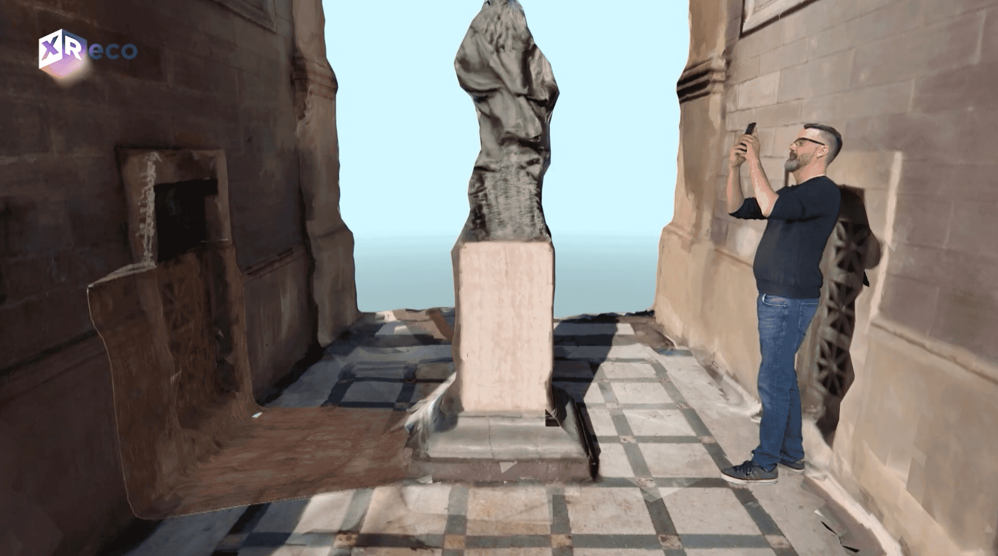 A man walks around a 3D model of a statue in the XReco virtual studio.