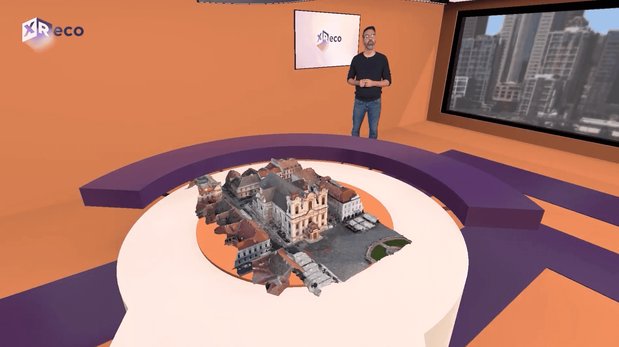 A presenter in the XReco virtual studio, showcasing a small 3D model of a building.